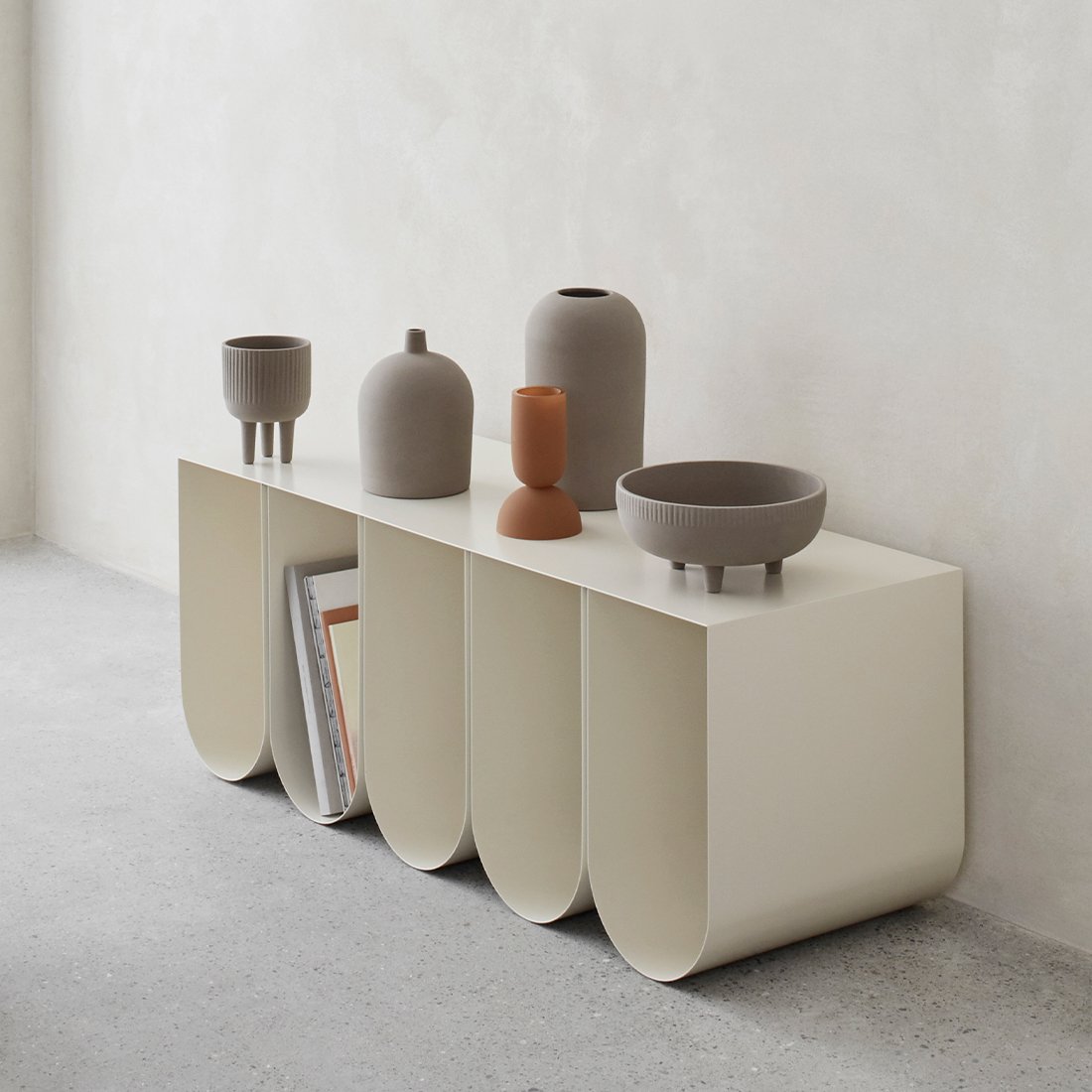 Terracotta medium bowl on white curved bench, all designed by Kristina Dam